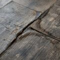 Beskadiget plastgulv med synlige slitage-, fugt- og misfarvningsskader der indikerer behov for udskiftning